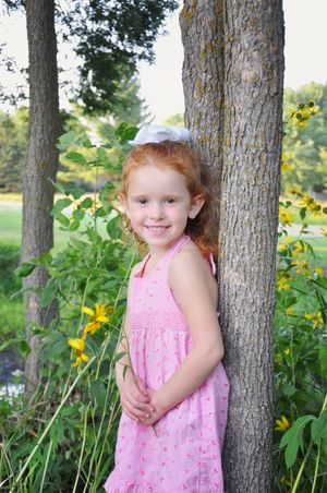 Portrait session among trees and yellow wildflowers in an outdoor garden setting.