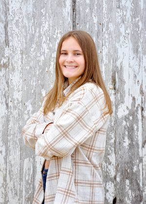 A series of casual portrait poses against a rustic white wooden wall wearing a plaid shirt.