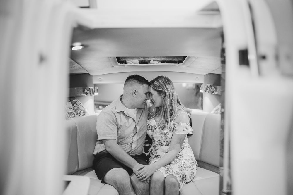 engaged couple sitting in boat cabin touching foreheads and smiling at belmar
