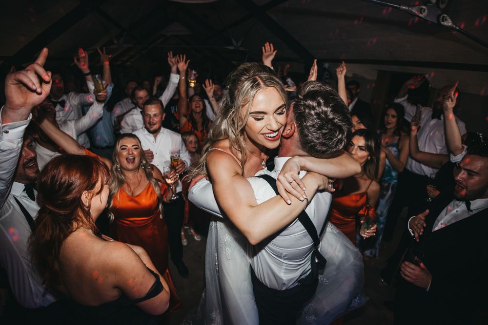 A bride jumping into the arms of her groom on the dance floor