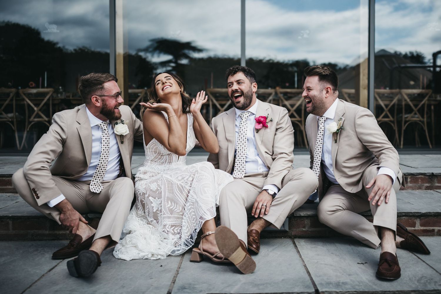 bride, groom and best men sat on steps at Thorpe Garden laughing
