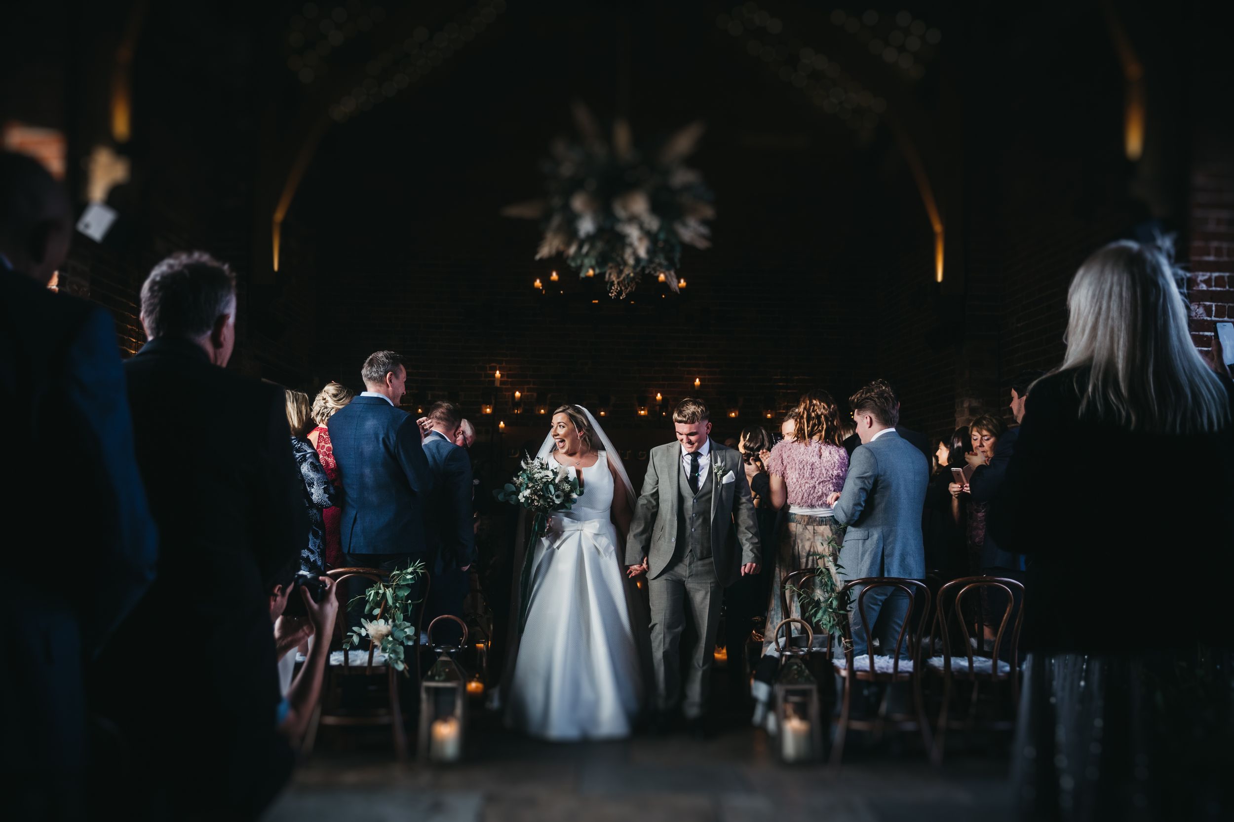 Hazel gap wedding barn a newly married couple exit the ceremony smiling at their guests