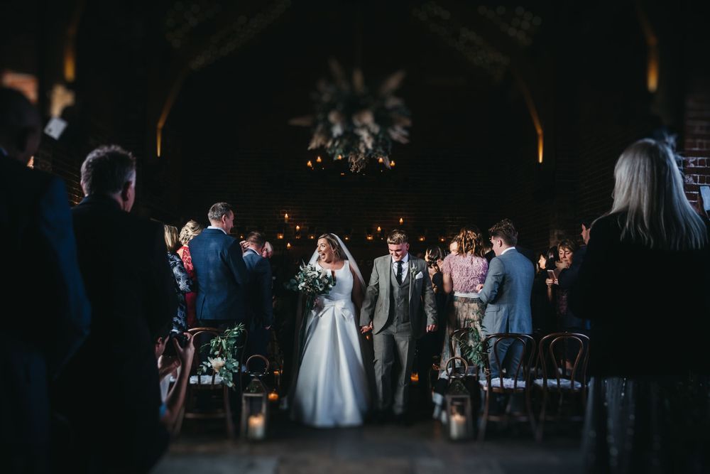 Hazel gap wedding barn a newly married couple exit the ceremony smiling at their guests