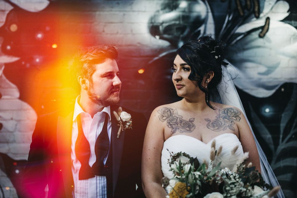 wedding couple looking at each at their wedding in front of graffiti
