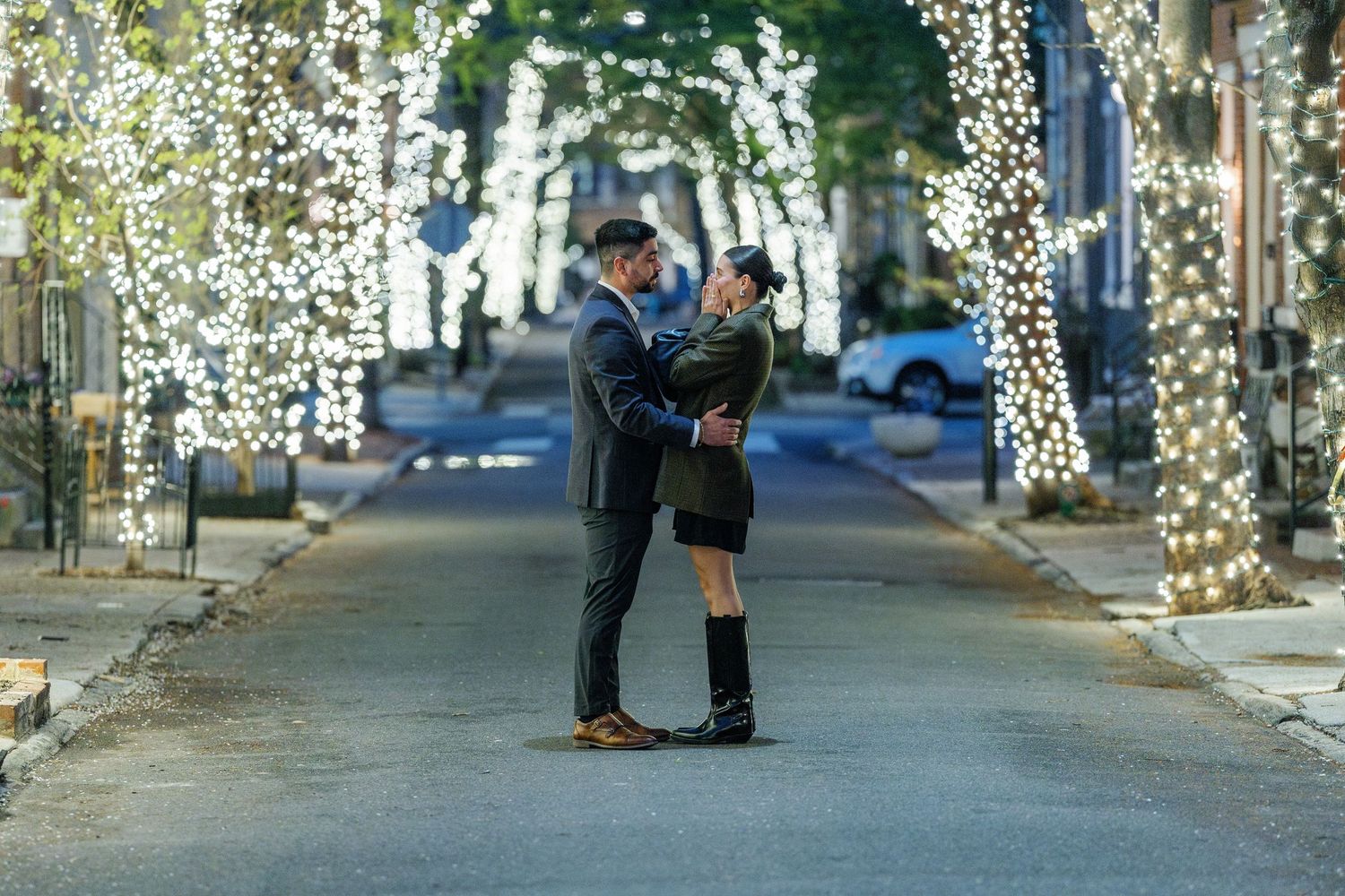 Surprise proposal moment captured on brick courtyard with historic arches in background.