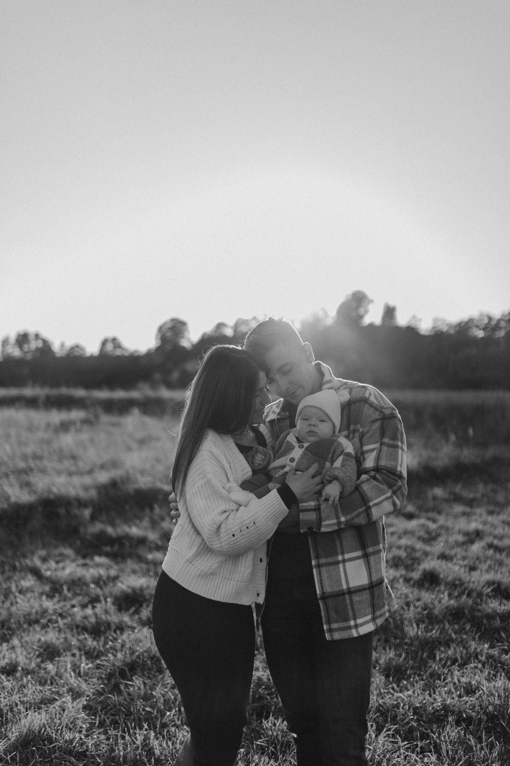 Black and white portrait of a family sharing an intimate moment outdoors.