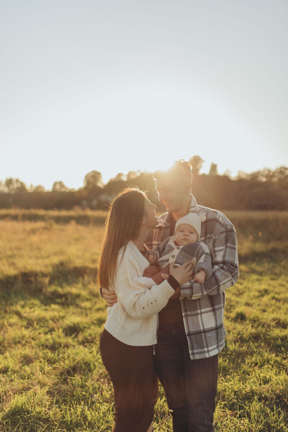 Family embracing together in a golden field at sunset.