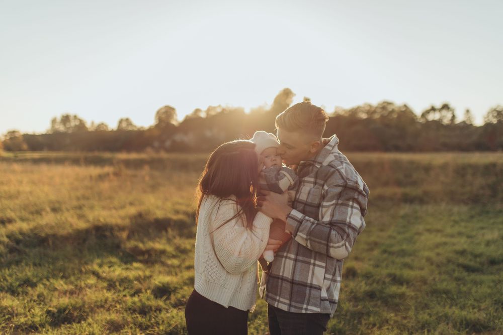 A romantic sunset moment between a couple standing together in a golden meadow.
