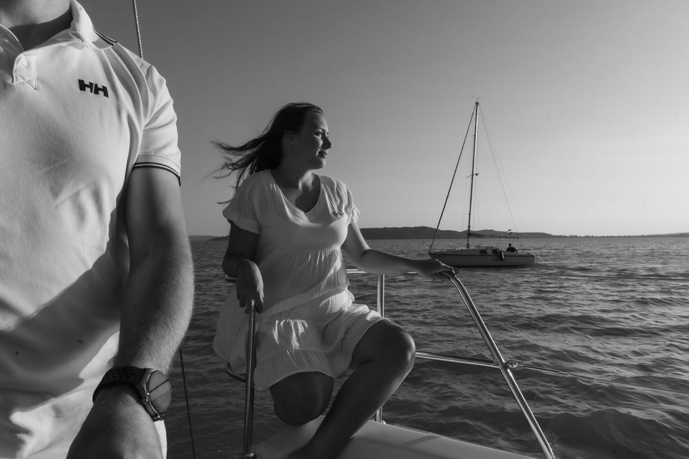 Black and white image of sailors on deck with wind blowing across the water.