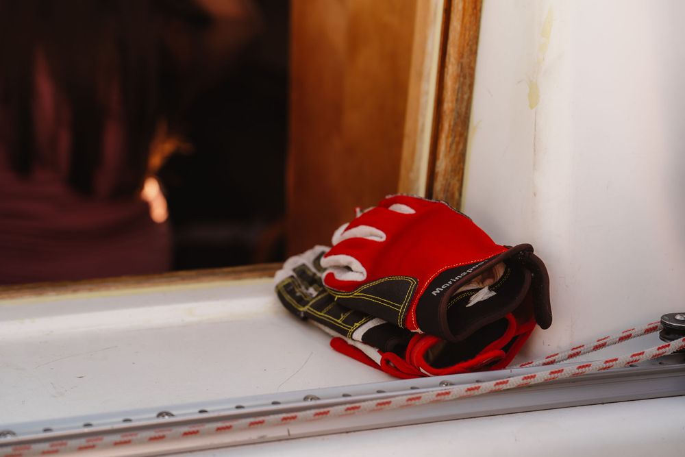 A red baseball glove sitting on a white windowsill with a fireplace in the background.