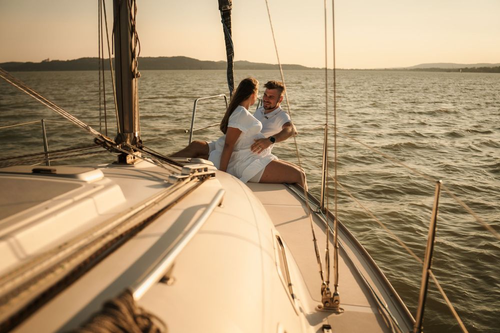 Couple enjoying a romantic sailing experience during sunset on a yacht deck.
