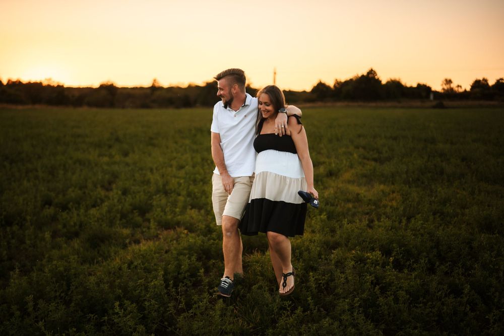 A romantic sunset walk through tall grass during a maternity session.