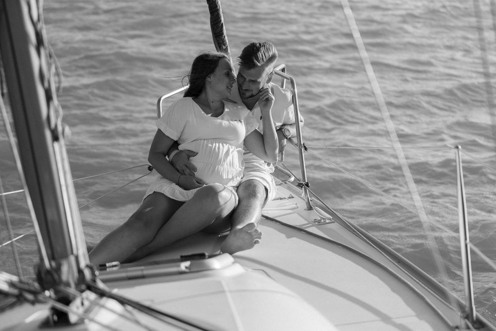 Black and white photo of two people embracing on a sailboat deck.
