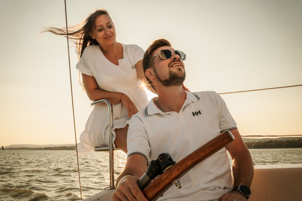 Couple enjoys sailing adventure together during sunset with person steering boat.