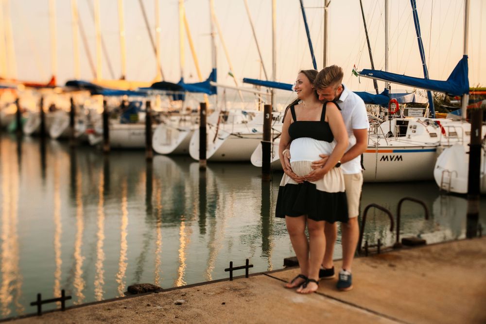 A romantic moment at a marina dock with boats and reflections at sunset.