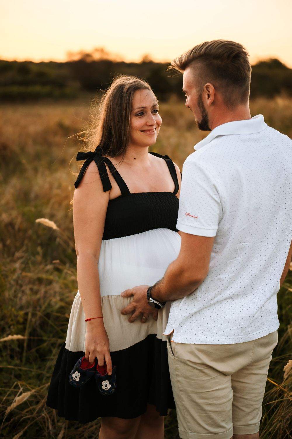 Couple embraces in wheat field wearing coordinated black and white outfits.