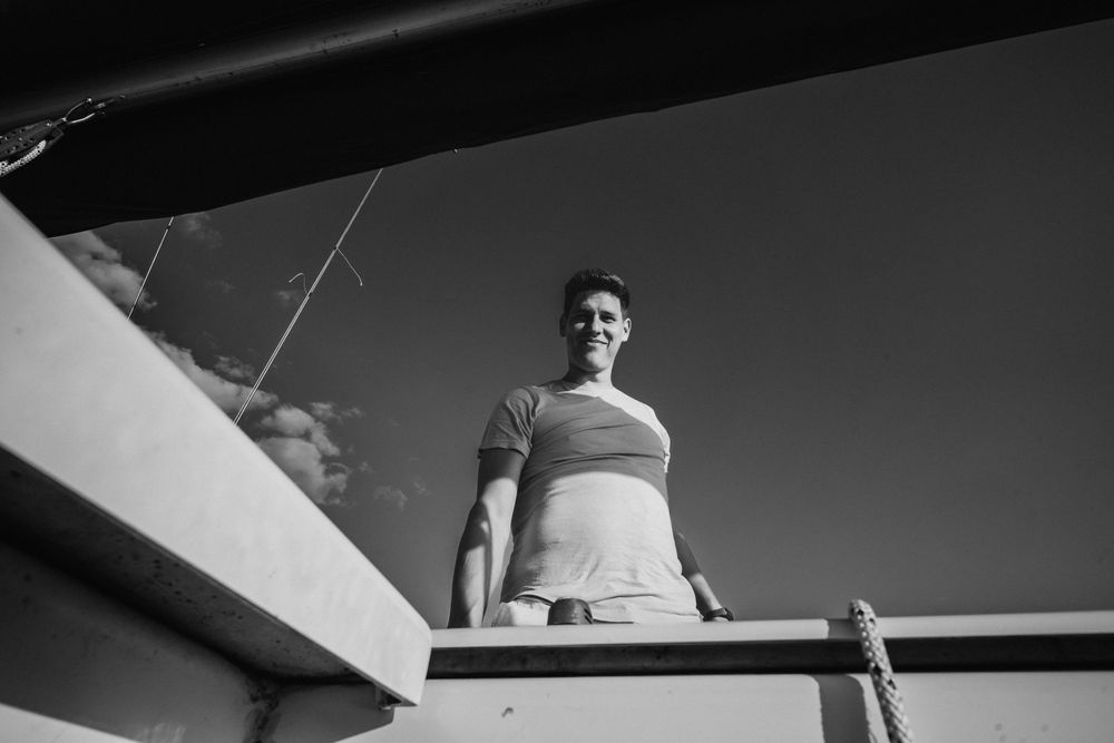 Low angle black and white shot of someone standing on a boat deck against clear sky.