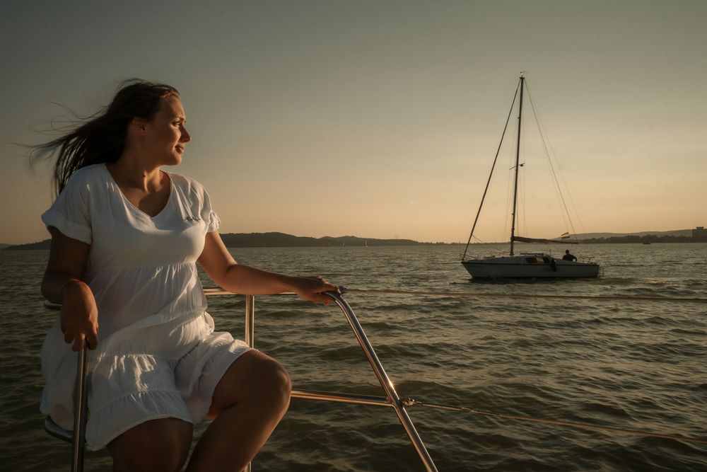 Sailor enjoying the sunset view from yacht deck with another boat in background.