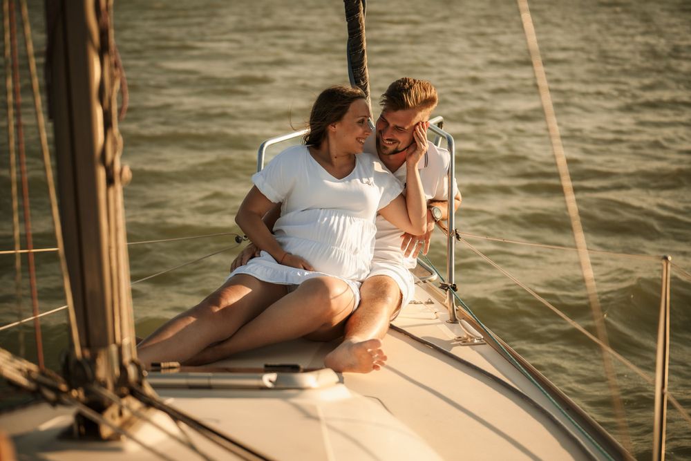Couple sharing a tender moment while sitting on a yacht deck during golden hour.