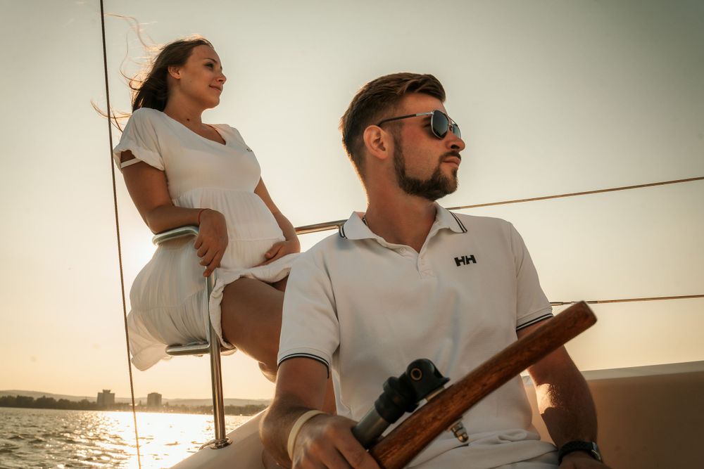 Couple in matching white outfits sailing together during golden hour.
