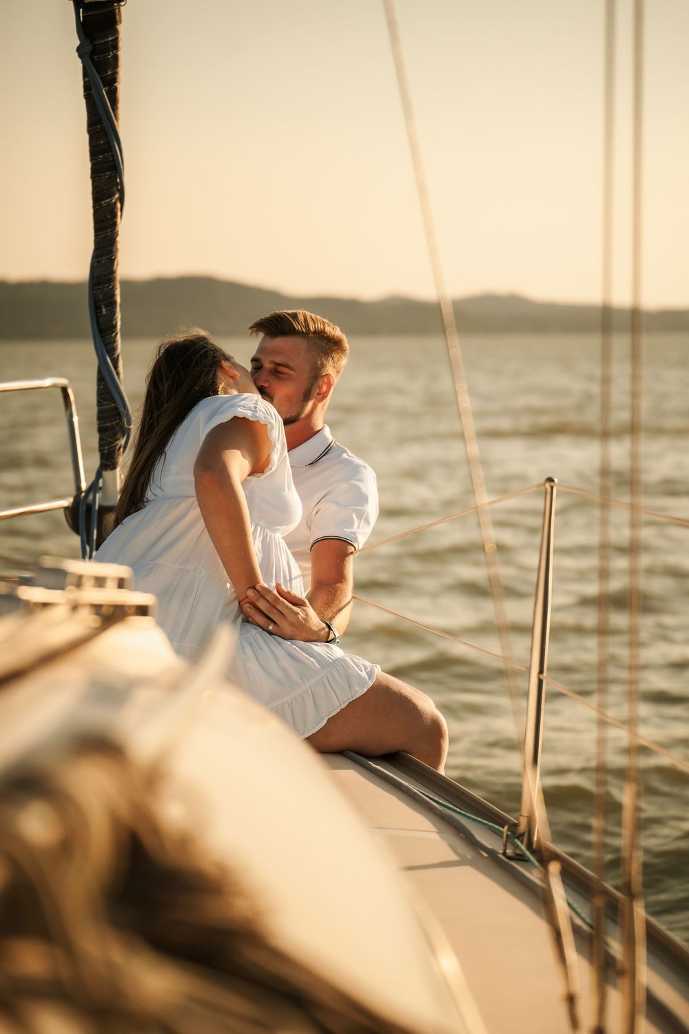 Intimate embrace between couple on yacht deck during sunset cruise.