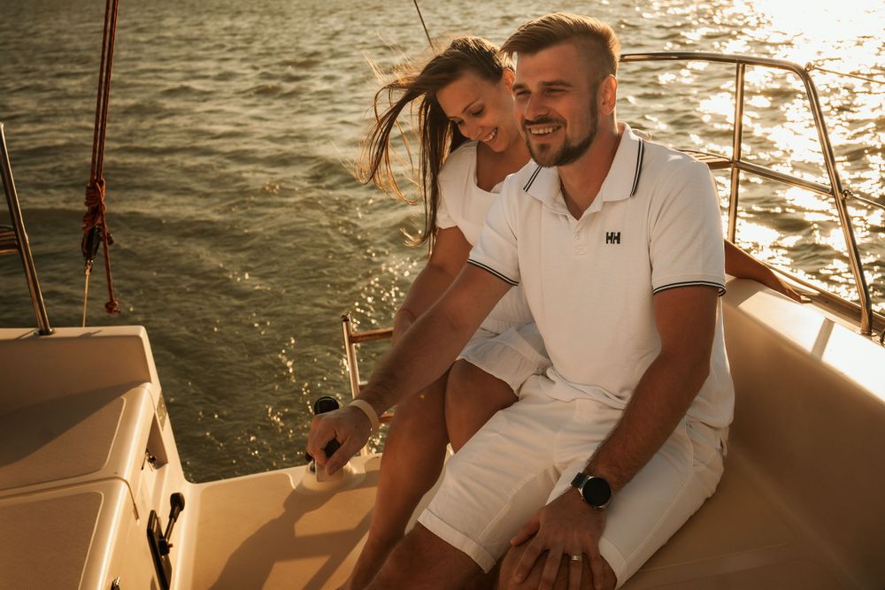 Two people sharing an intimate moment while sailing on a boat at golden hour.