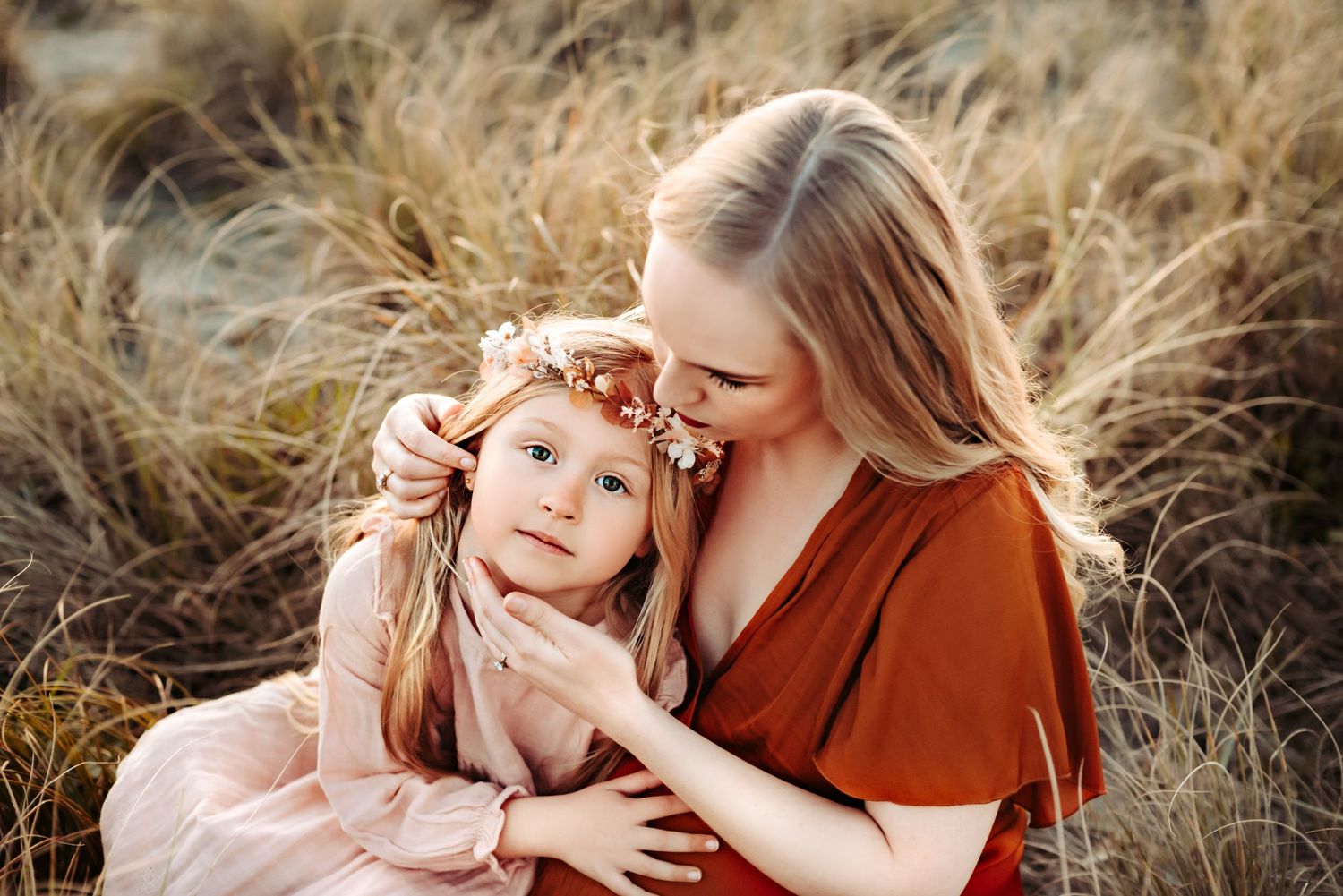 A tender moment captured in a wheat field with warm golden lighting and earth-toned clothing.