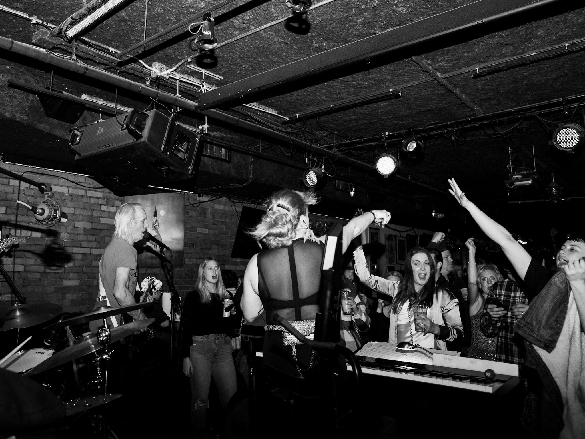 black and white image behind a rock band playing to a crowded venue
