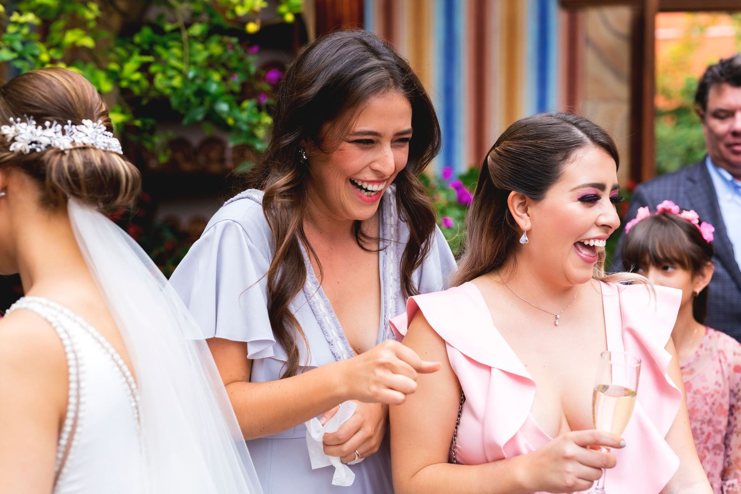 A group enjoying cheerful conversation during a wedding celebration in a garden setting.