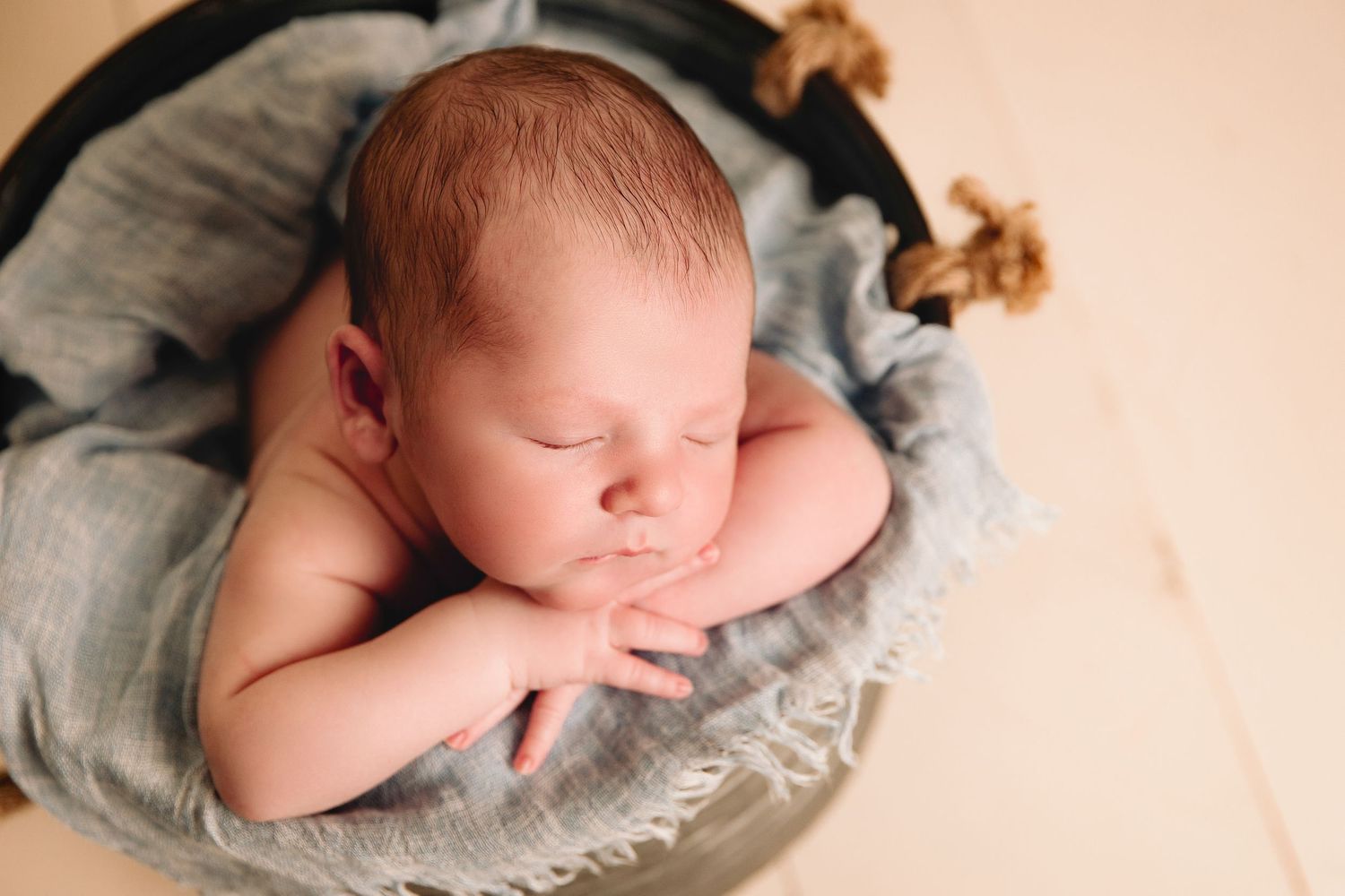 close up of infant in a newborn photography prop bucket