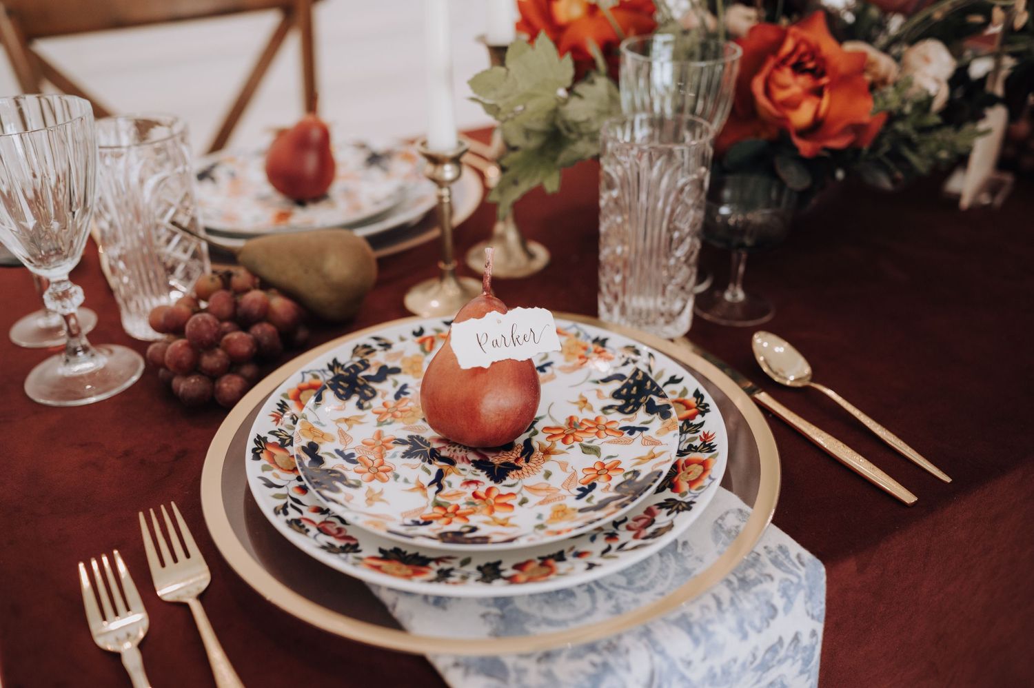 Place setting with blue and white patterned china, crystal stemware, and terracotta accents.