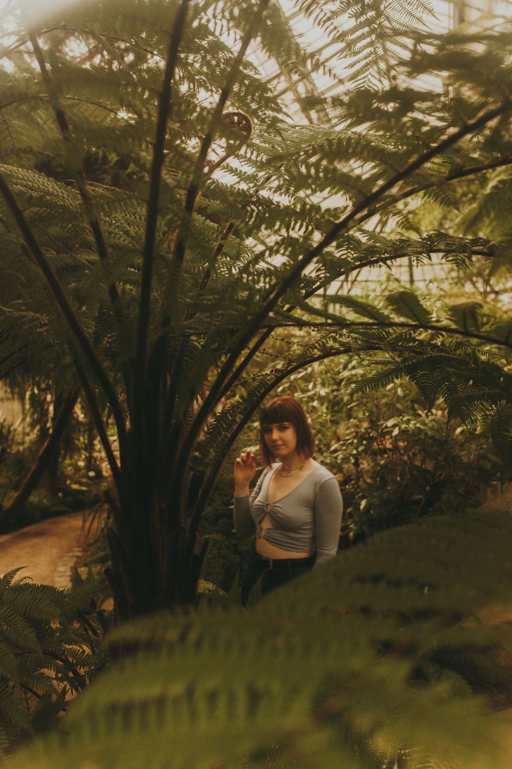 Photograph of young woman in a botanical garden through the leaves.