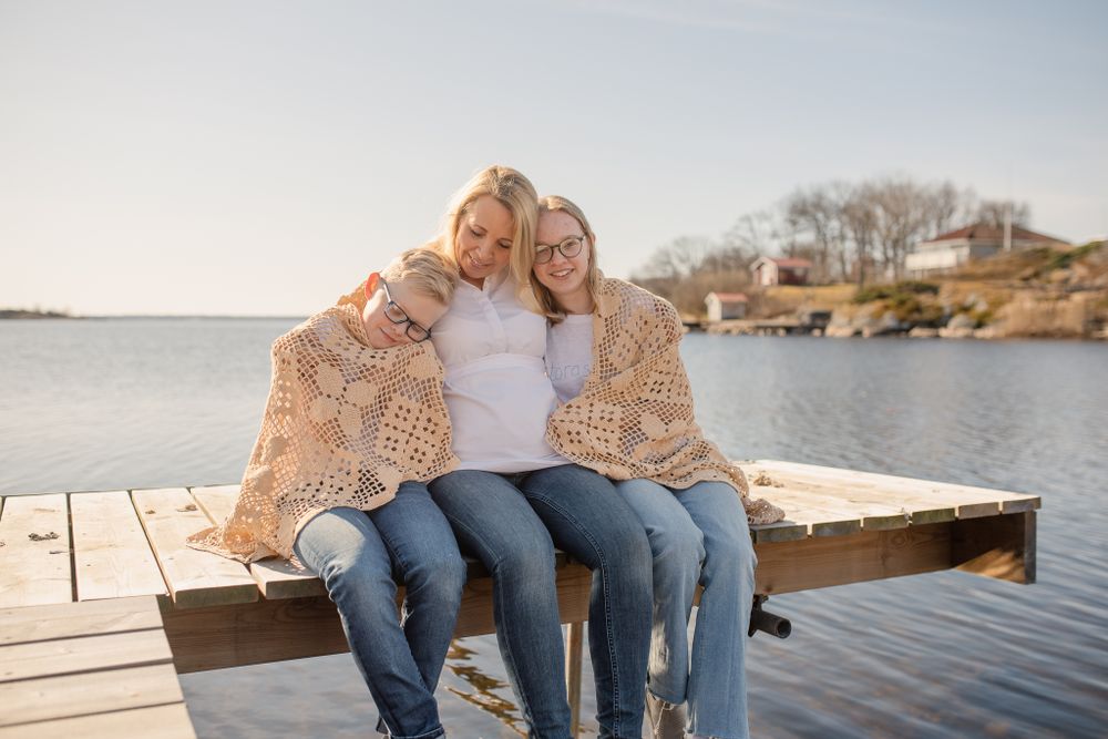 Sitting together on wooden dock during sunset wearing cozy beige cardigans.