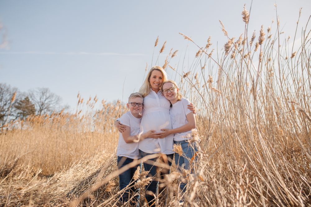 Embracing in tall golden reeds during sunset maternity photo session.