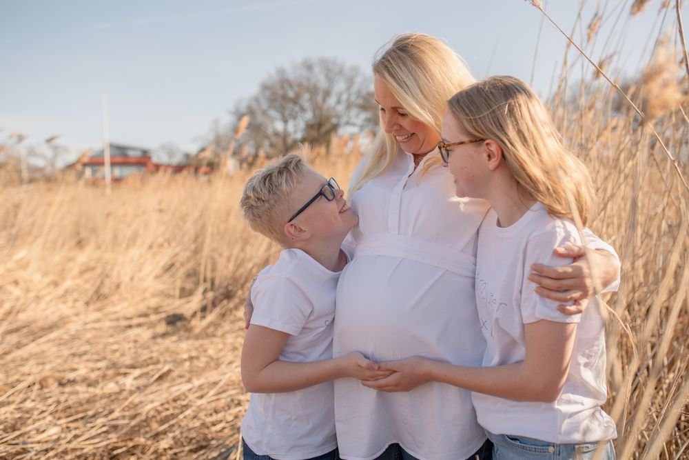 Sweet family moment captured in golden sunlight amongst dried reeds.