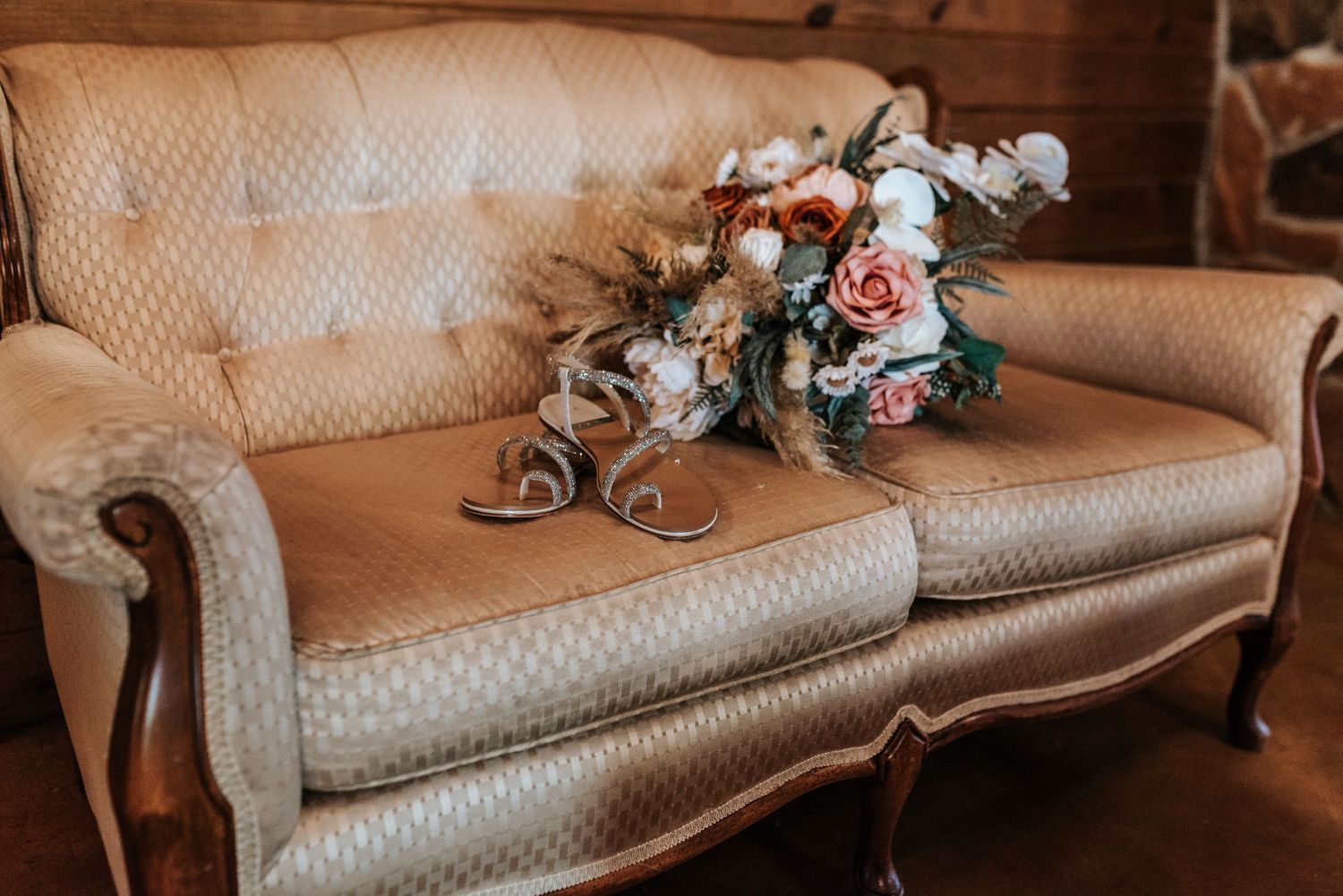 Vintage beige sofa with pink and white floral arrangement in rustic setting.