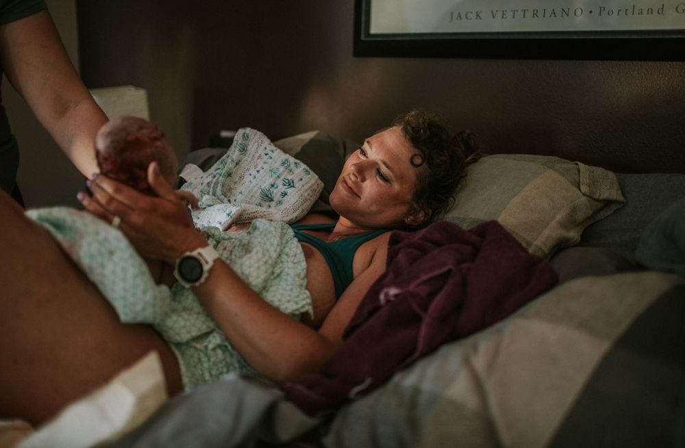 birthing person holds infant for first time home birth photography portland oregon