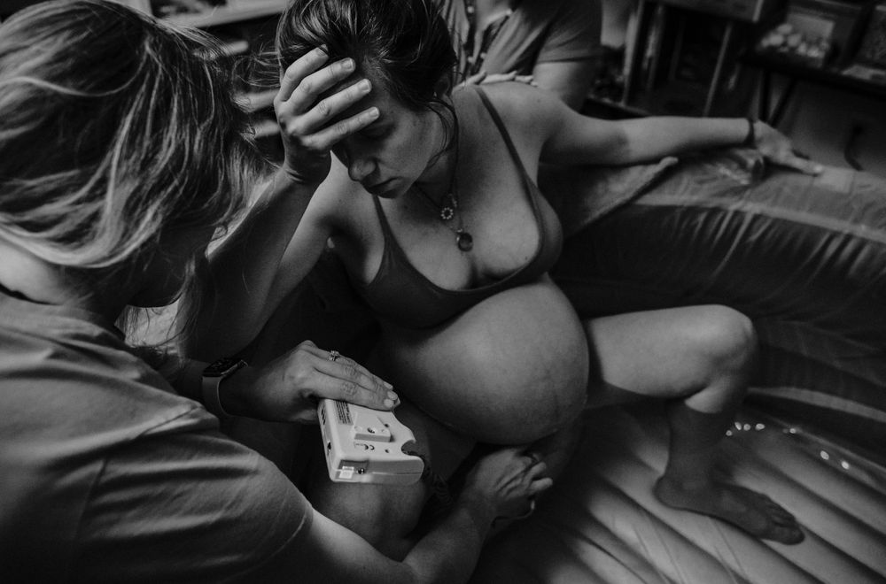 birthin person holds head while midwife checks vitals home water birth portland oregon photographer