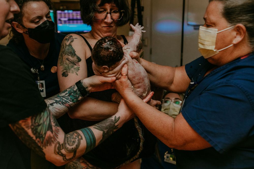 birthing person grabs newborn after fast hospital birth portland oregon birth photographer