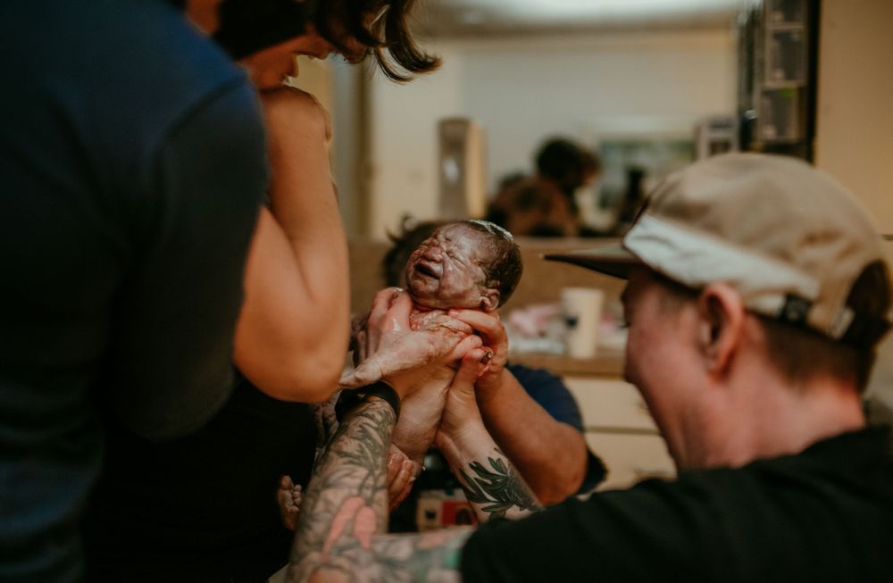 partner catches newborn during fast hospital birth portland oregon birth photographer doula kimberly marie kimble