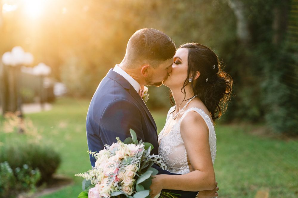 Romantic wedding portrait at golden hour with sunlit garden backdrop and pastel bouquet.
