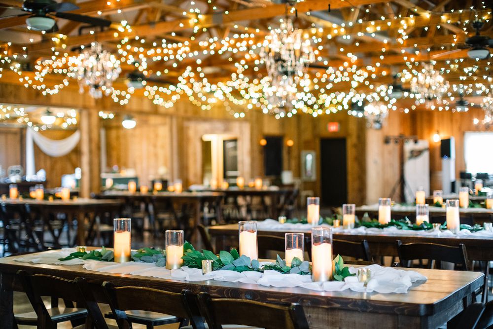 Rustic wedding reception venue with wooden tables and twinkling fairy lights overhead.