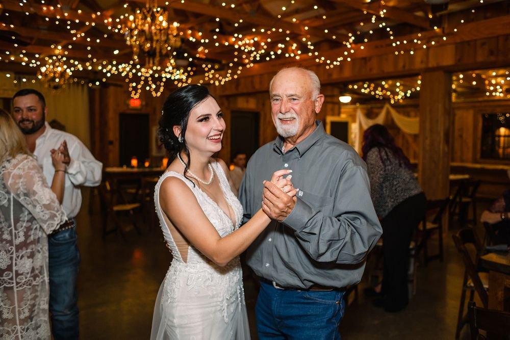 Reception dance moment captured under warm lighting in rustic barn venue.