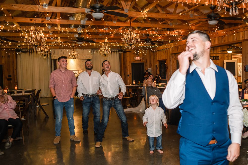 Festive indoor celebration with guests dancing under rustic wooden beams and elegant chandeliers.