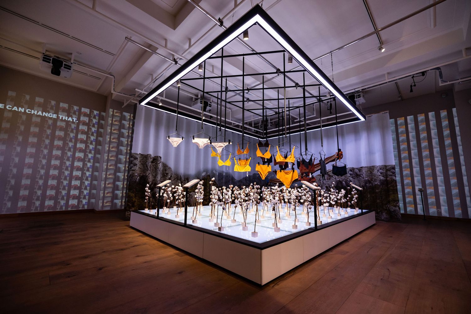 Large illuminated display of designer shoes arranged in a modern museum-like exhibit with geometric lighting installation.