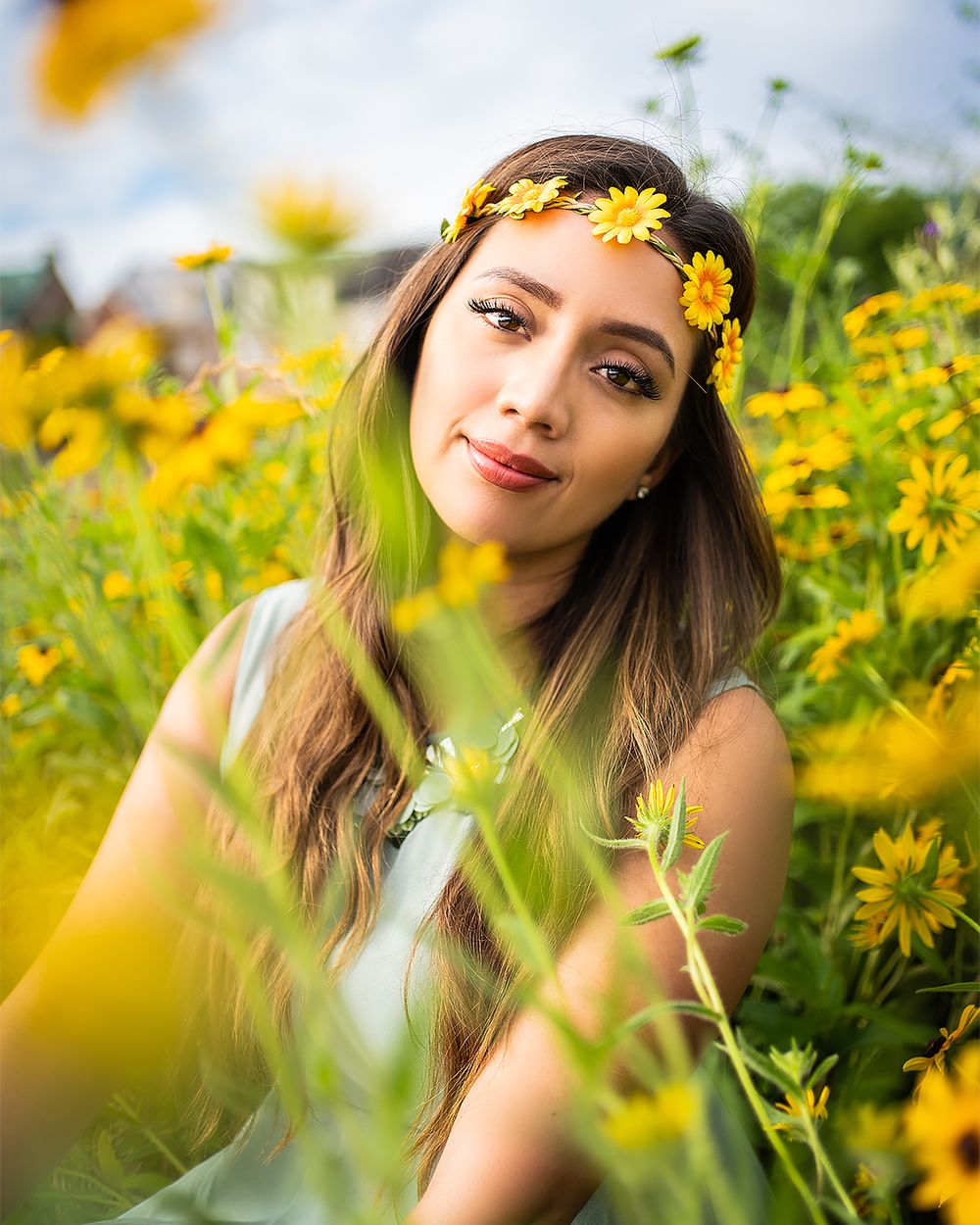Portrait of person wearing yellow flower crown in sunny wildflower field.