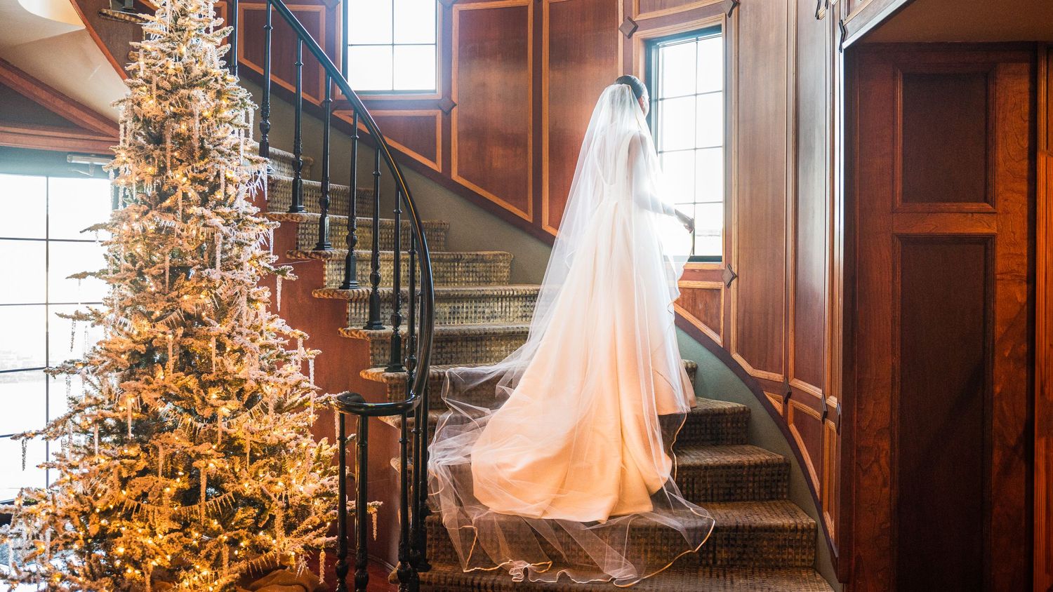 Bride posing on Lands End's staircase with Christmas decorations, looking out the window