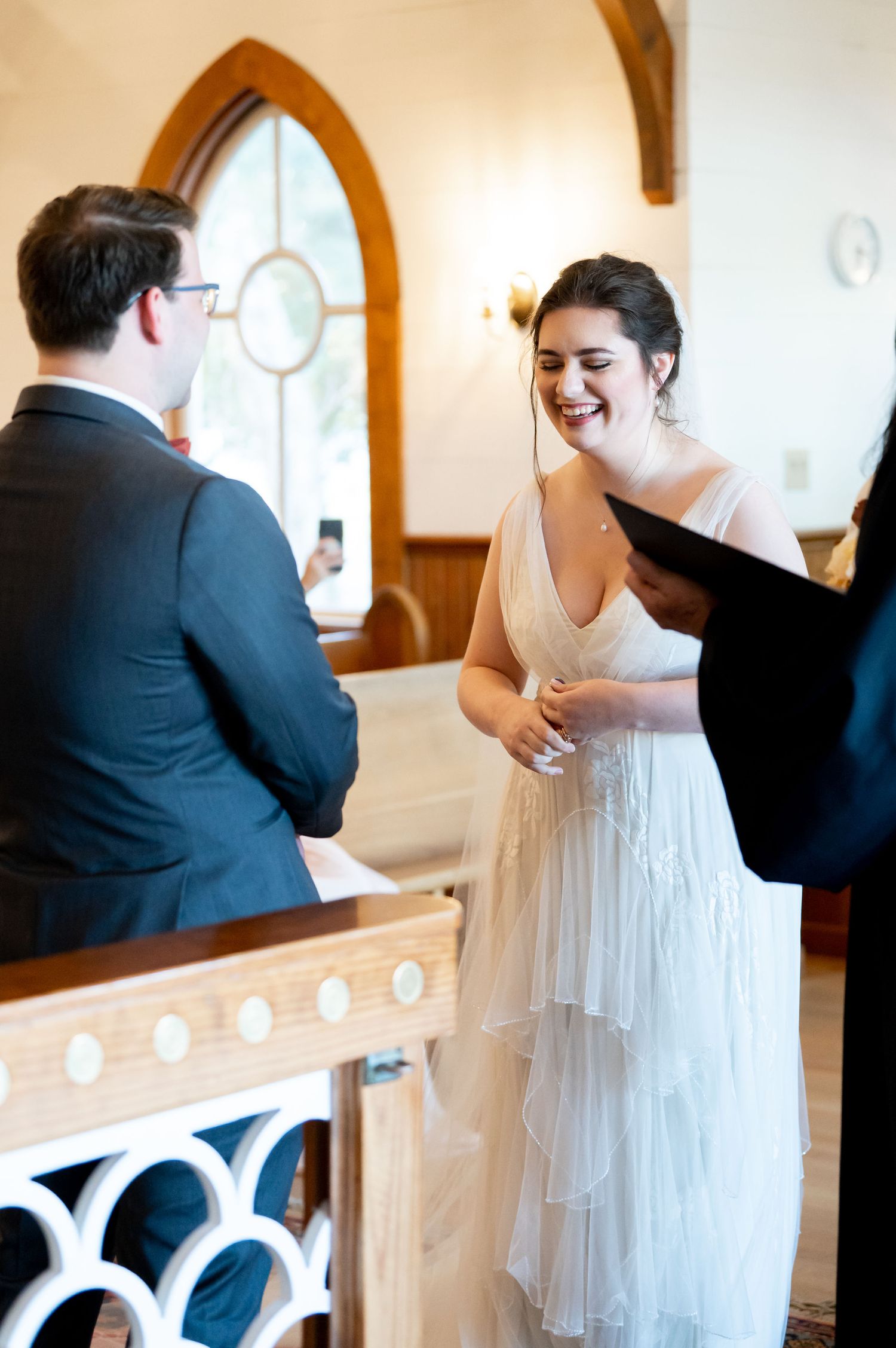 Joyful moment during wedding ceremony in a chapel with arched windows and wooden details.