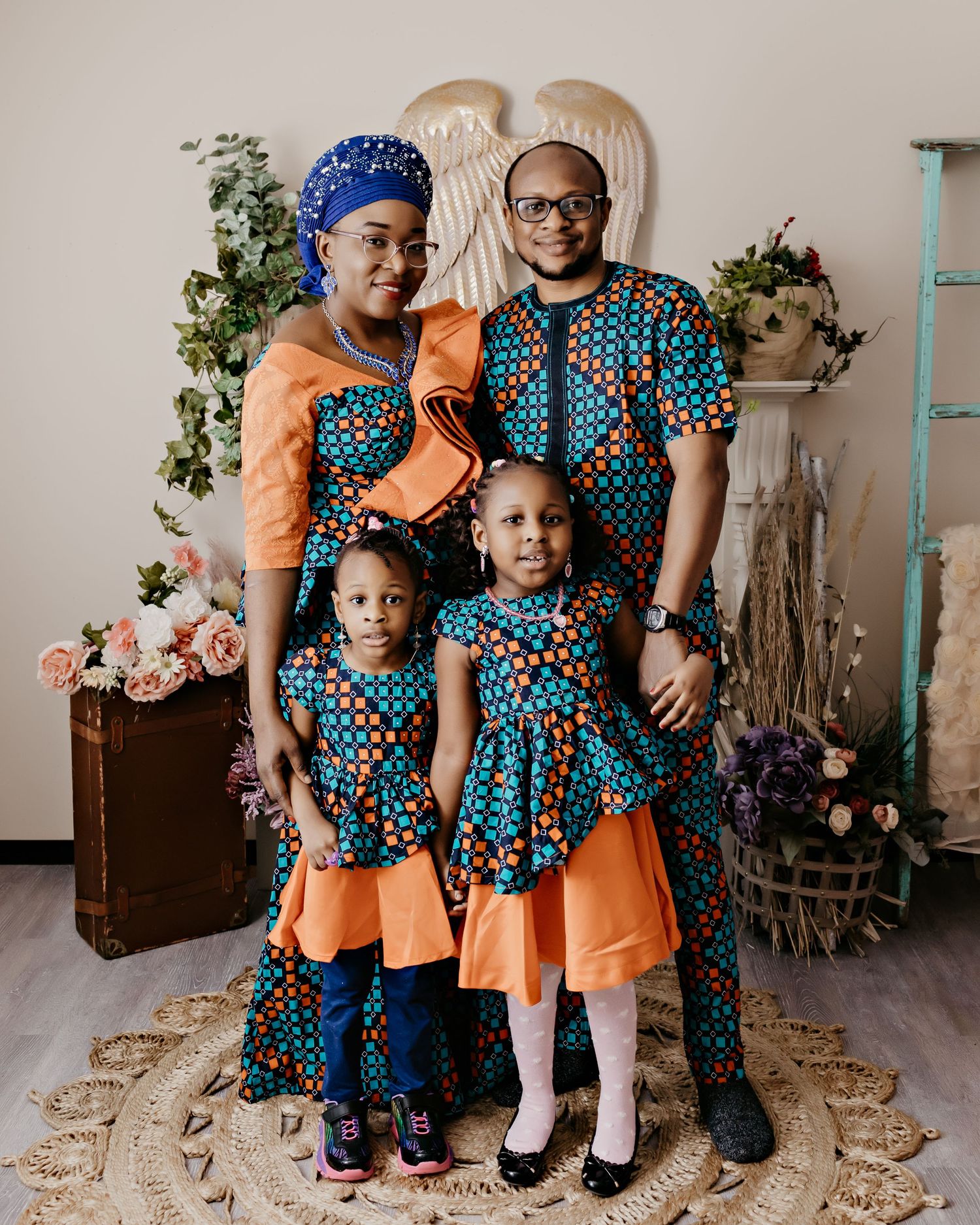 Family wearing matching blue and orange patterned outfits poses against decorative backdrop.