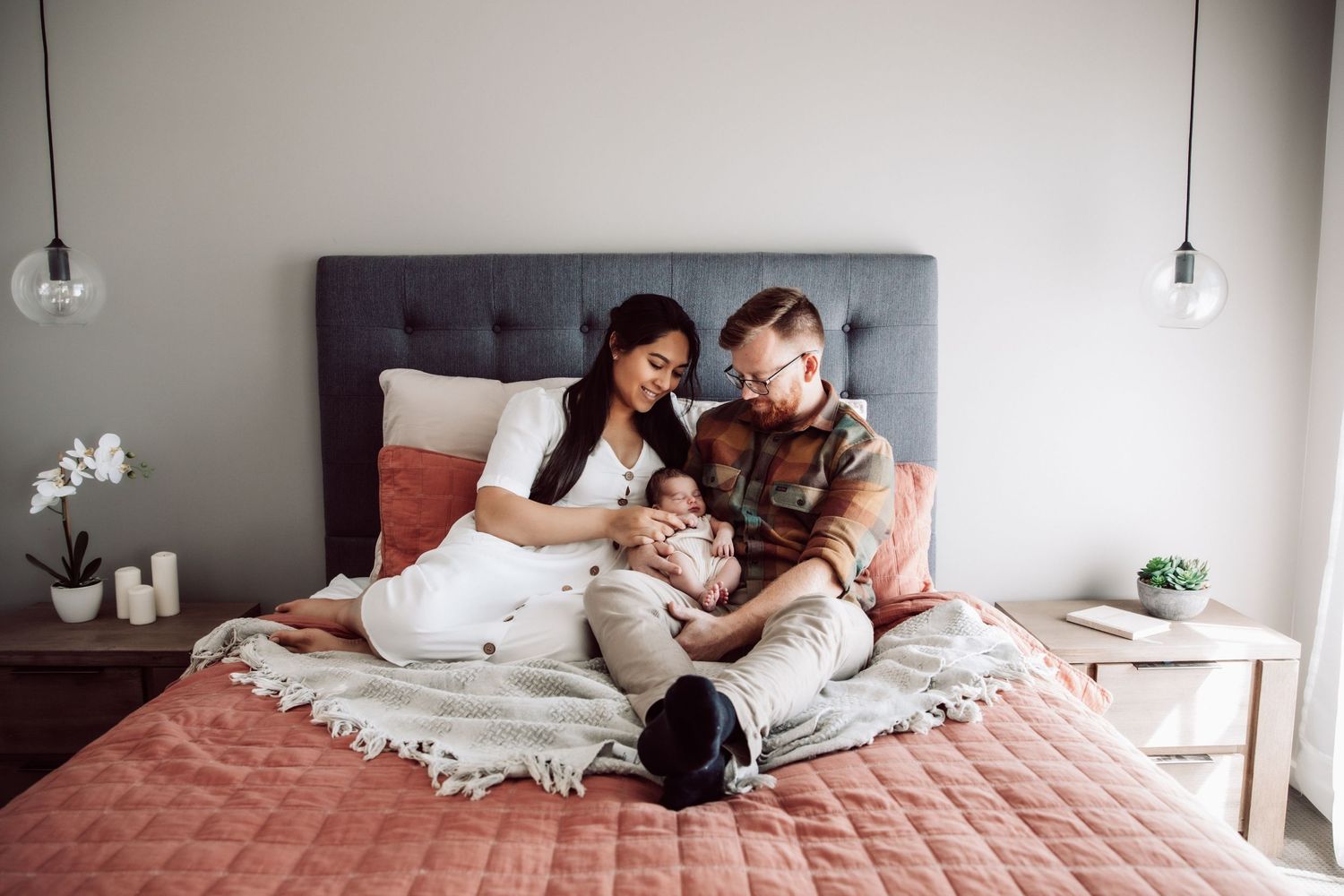 Intimate lifestyle family photography session on coral bedding in modern bedroom.